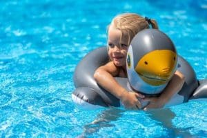 Solar pool heating allows your family to swim year round, like this girl floating in a pool raft.